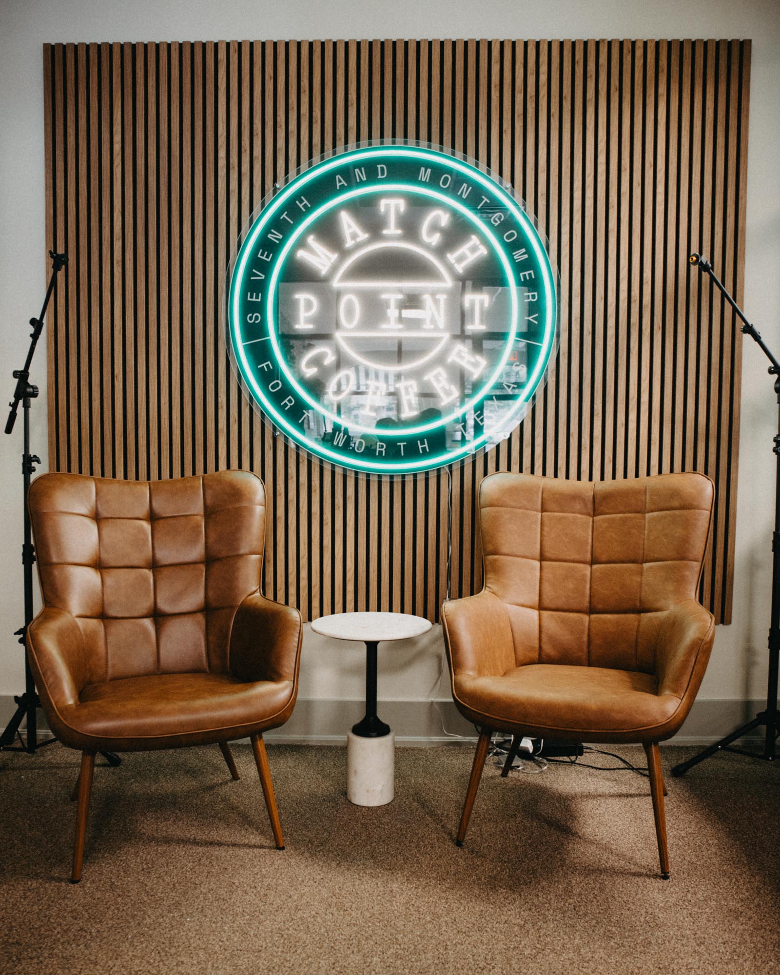 podcast room with neon signs and comfortable leather chairs