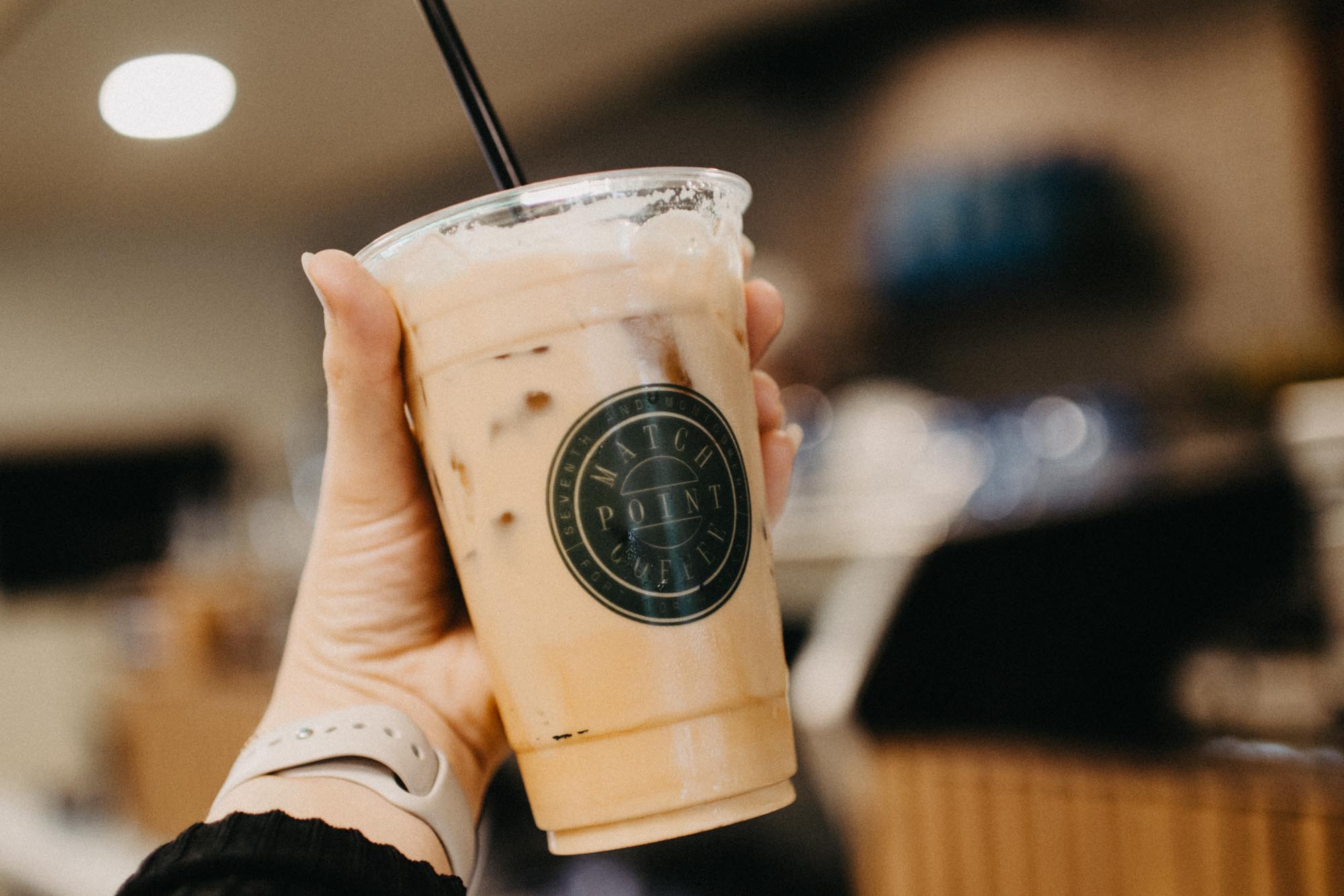 iced coffee with match point coffee logo held by hand